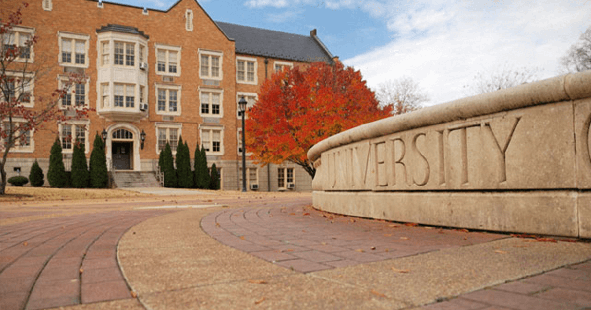 Sidewalk and large building on a university campus. 