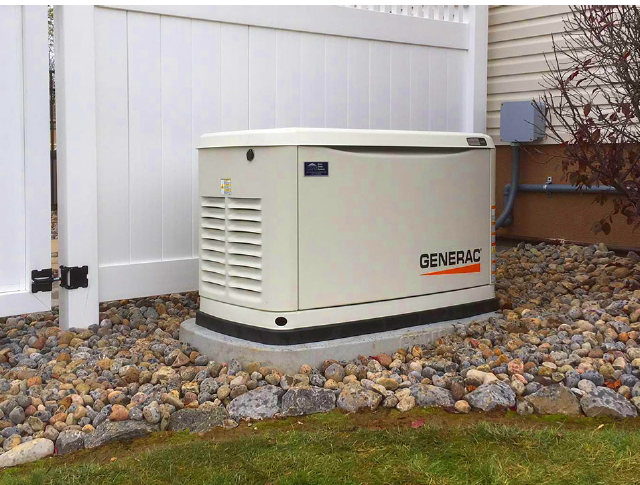 Generac standby generator outside of home on gravel rocks.